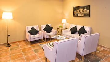 Una habitación con dos sillones, un sofá, una mesita y una lámpara de pie.