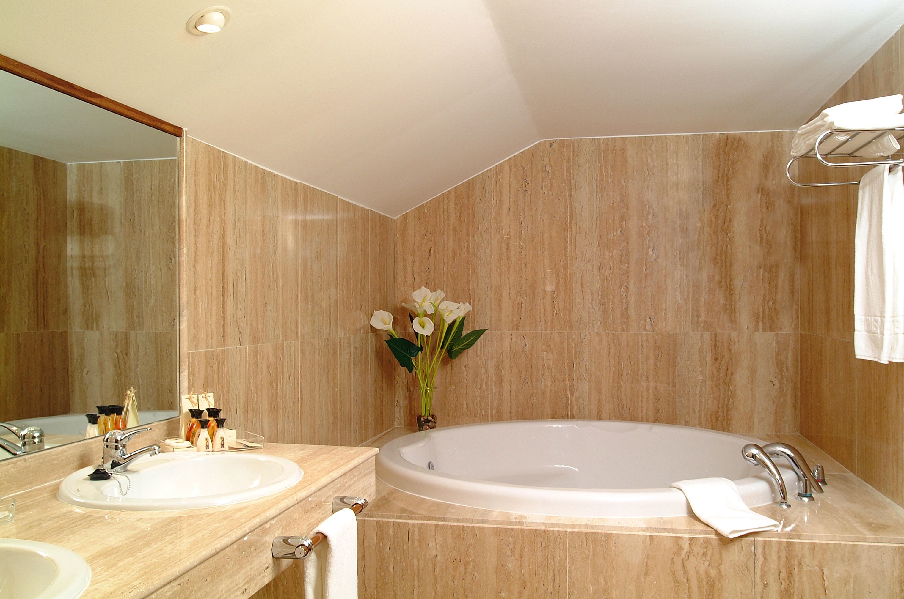 Un bagno con due lavandini, una vasca da bagno spaziosa e uno specchio.
