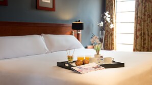 A neatly made bed with white linens, a tray with croissants, a cup of coffee, and a glass of orange juice on the bed. - Hotel Segovia Sierra de Guadarrama (El Espinar)