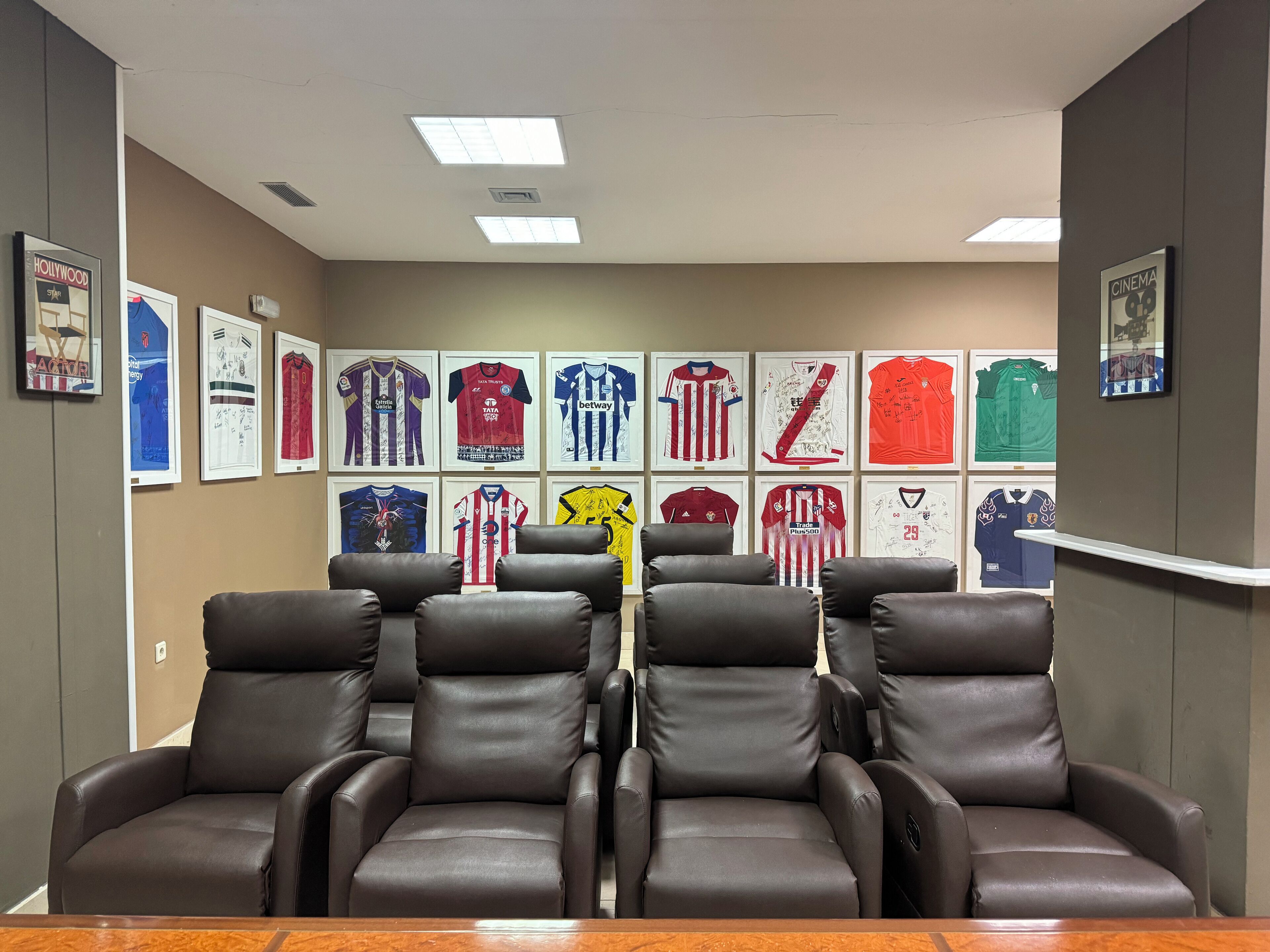 A conference room with a row of framed sports jerseys on the wall and leather chairs in the foreground.