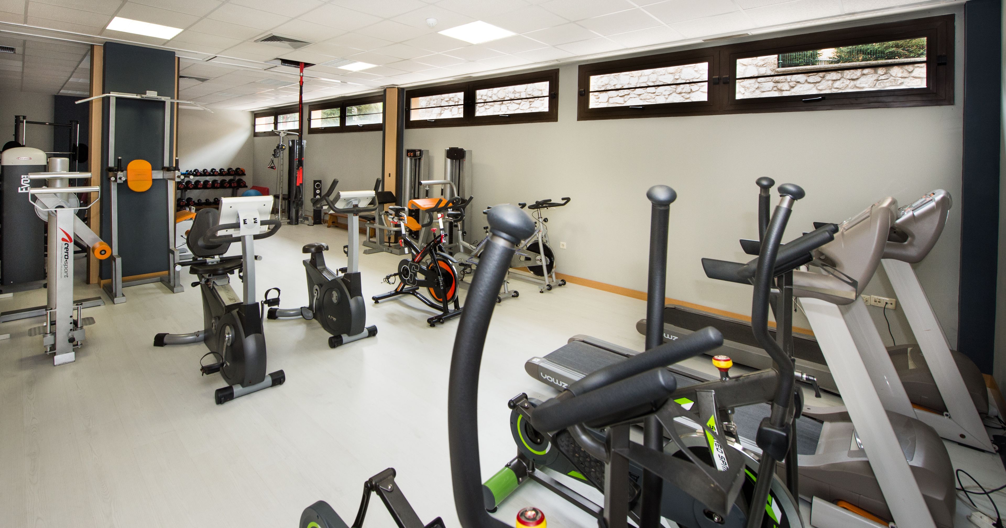 A gym with various exercise equipment, including treadmills, stationary bikes, and weight machines.