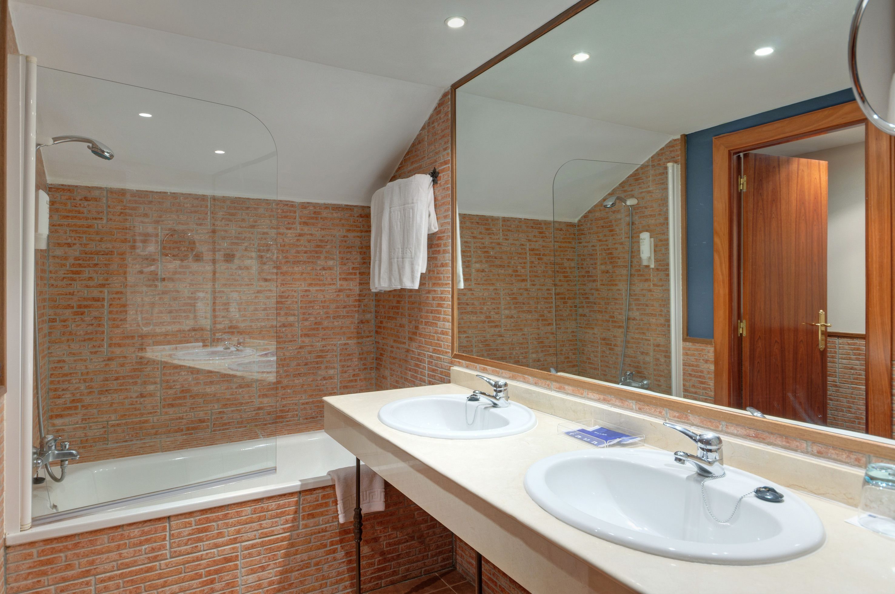 Un baño moderno con dos lavamanos, un espejo grande y una ducha.