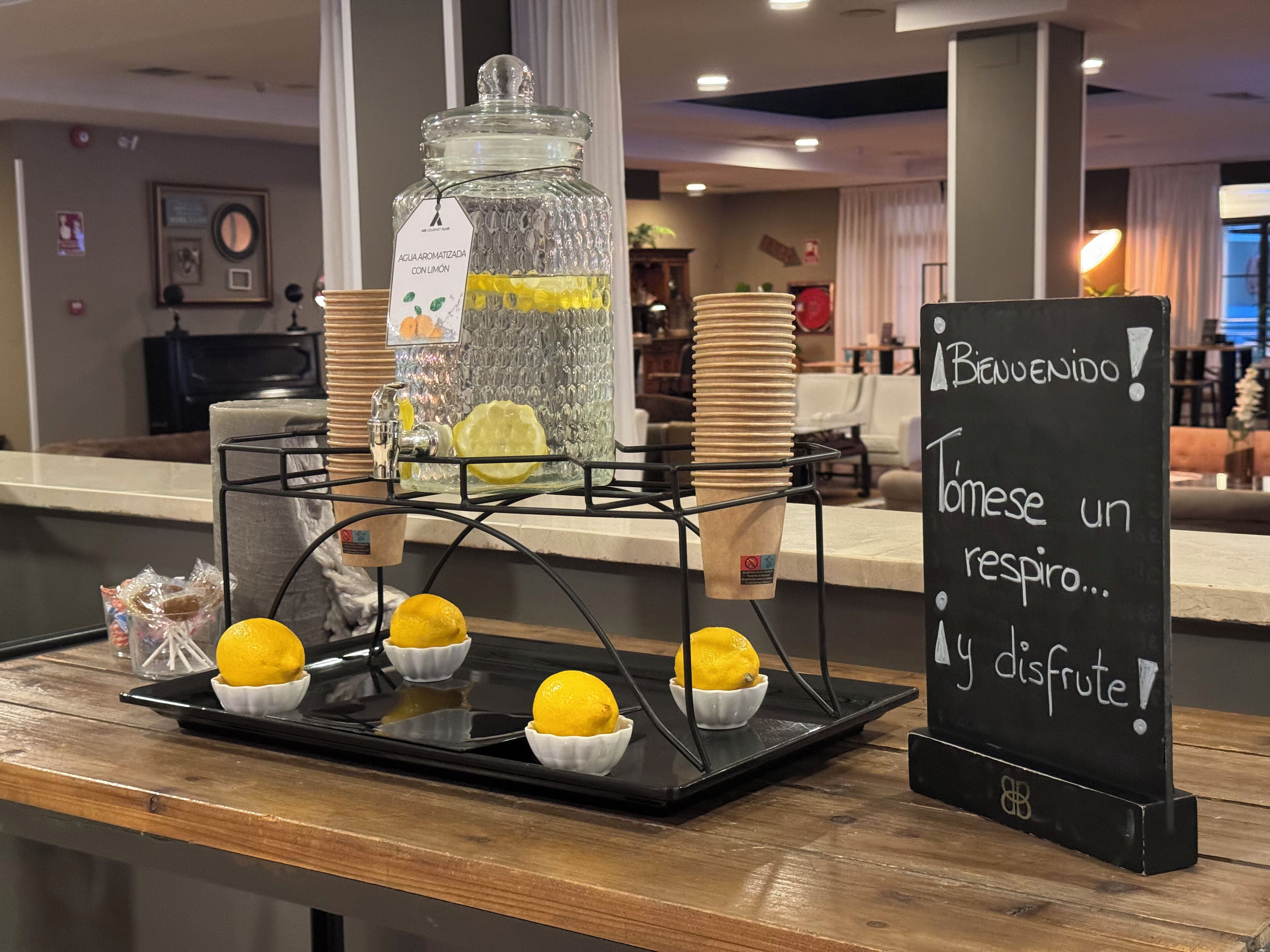 Un puesto de bebidas con rodajas de limón y un letrero en español.