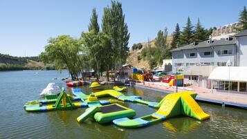 Enjoy water playtime with inflatable slides and pools in a serene lakeside setting surrounded by trees and residential areas.