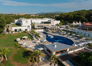 A hotel with a swimming pool, outdoor seating, and a view of the surrounding landscape.