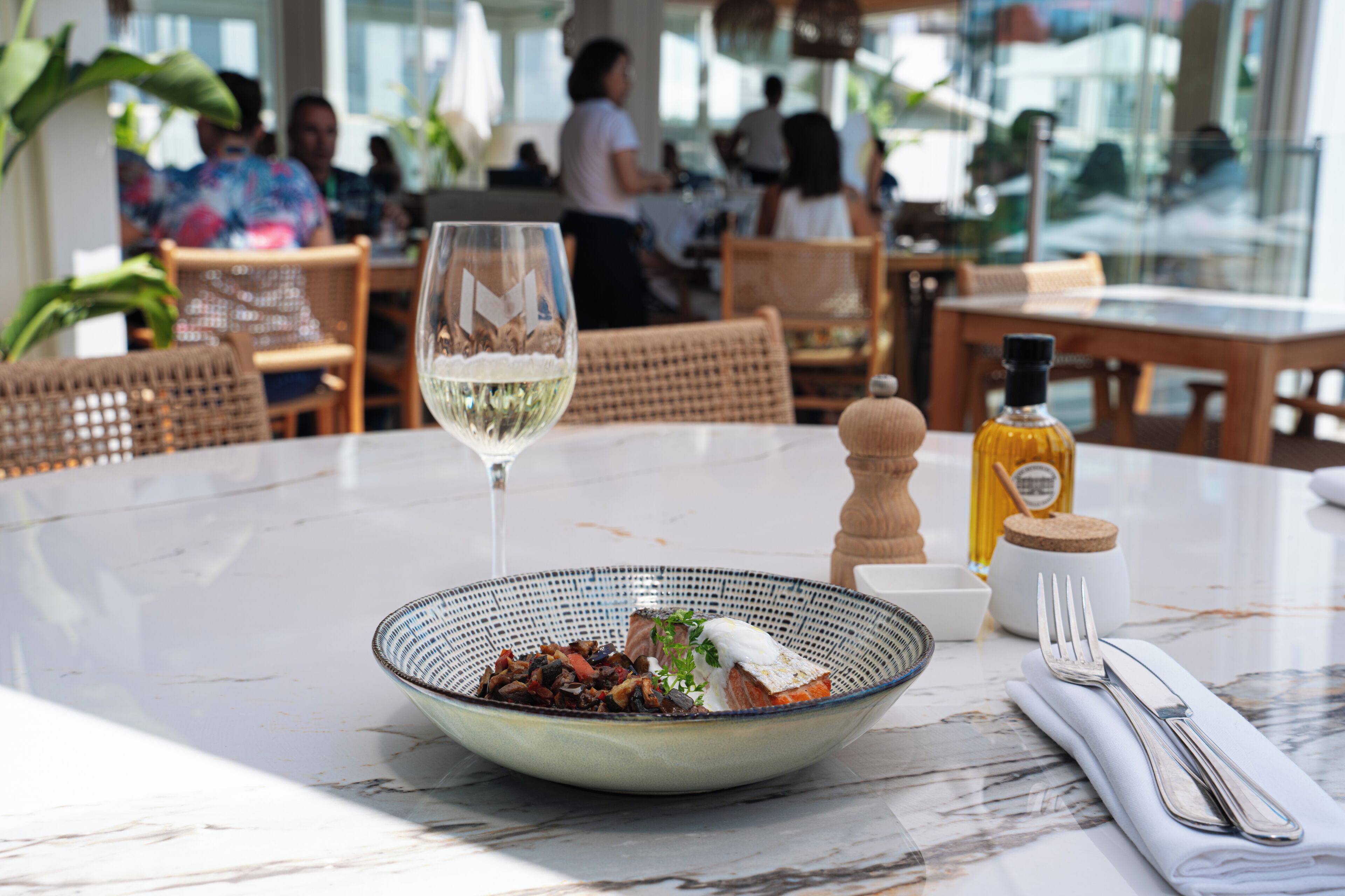 Une table à manger avec un bol de nourriture, un verre à vin et des couverts.