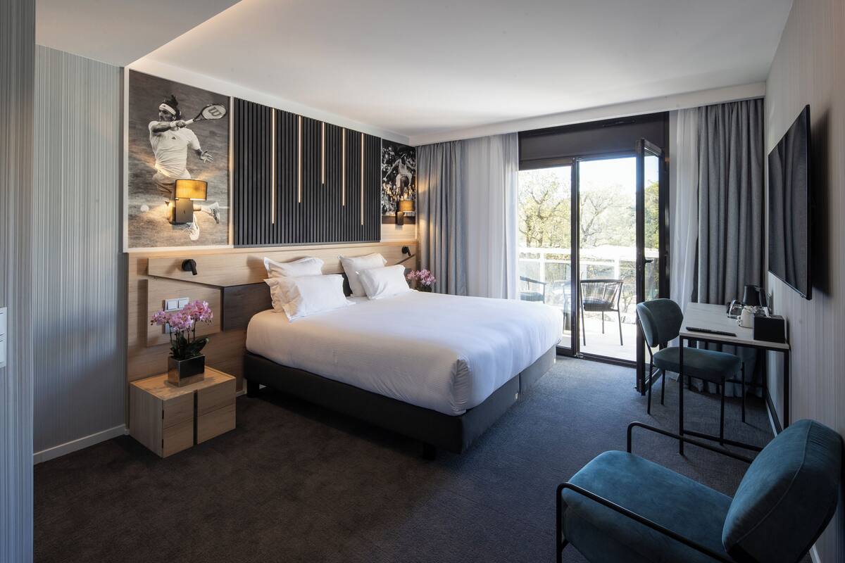 A modern hotel room with a large bed, bedside tables, a desk, and a chair.
