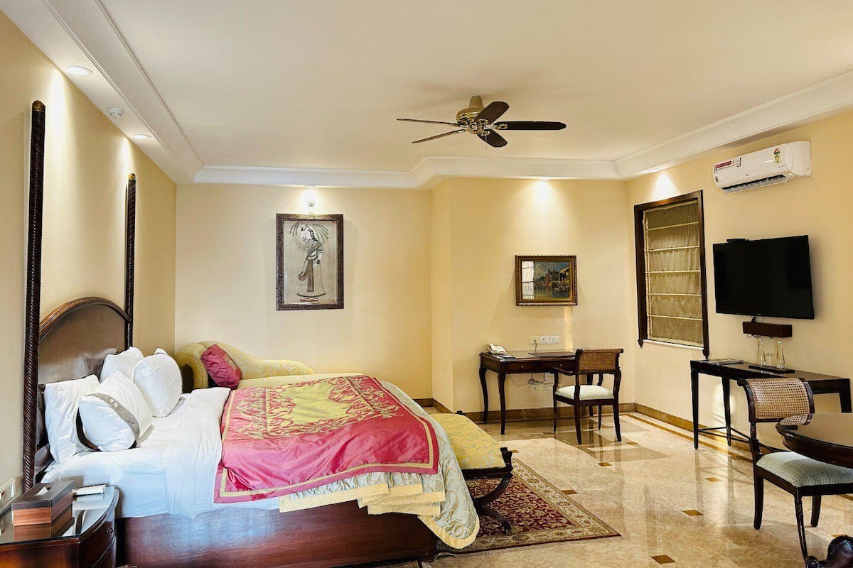 Une chambre d’hôtel équipée d’un lit, d’un ventilateur de plafond, d’une télévision, d’un bureau et d’une chaise.