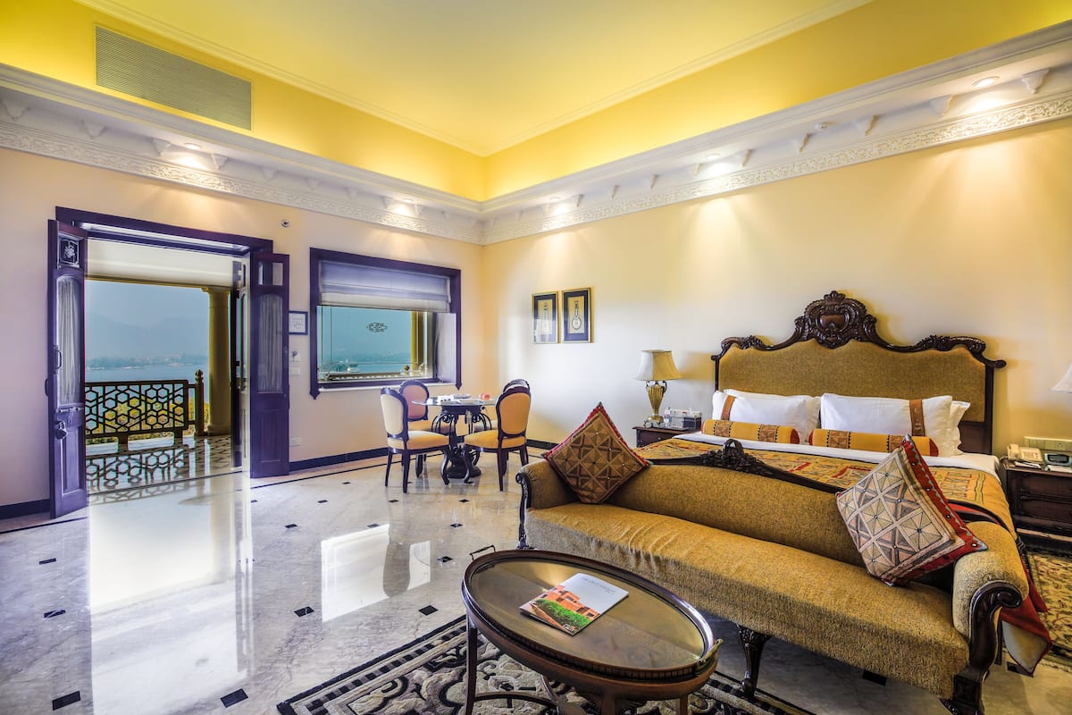 Une chambre d’hôtel avec un canapé, une table, un balcon avec vue et un coin repas comprenant des chaises et une table.