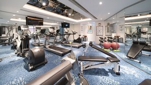 Une salle de sport moderne équipée de tapis de course, de vélos elliptiques, de poids libres et de ballons d’exercice.