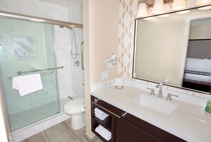 Ein modernes Badezimmer mit Duschkabine aus Glas, Toilette, Waschtisch mit großem Spiegel und Waschbecken.