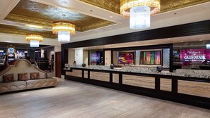 Un hall d’hôtel comprenant un comptoir d’accueil, un canapé agrémenté de coussins décoratifs et un lustre.