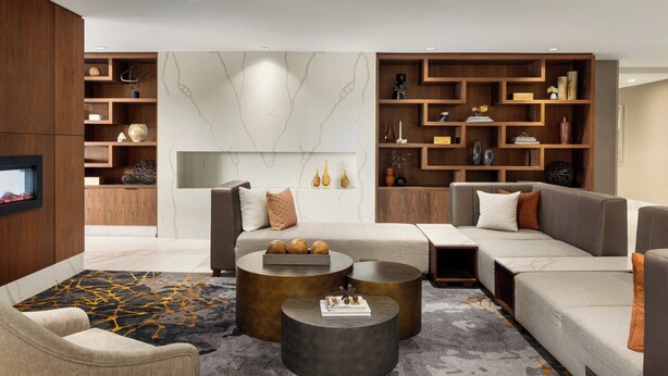 A modern living room with a sectional sofa, two coffee tables, and built-in wooden shelving.