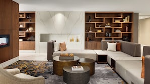 Un salon moderne avec un canapé d’angle, deux tables basses et des étagères encastrées en bois.