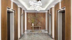 A modern hallway with wooden paneling, a central console table with a vase, and a unique ceiling light fixture.
