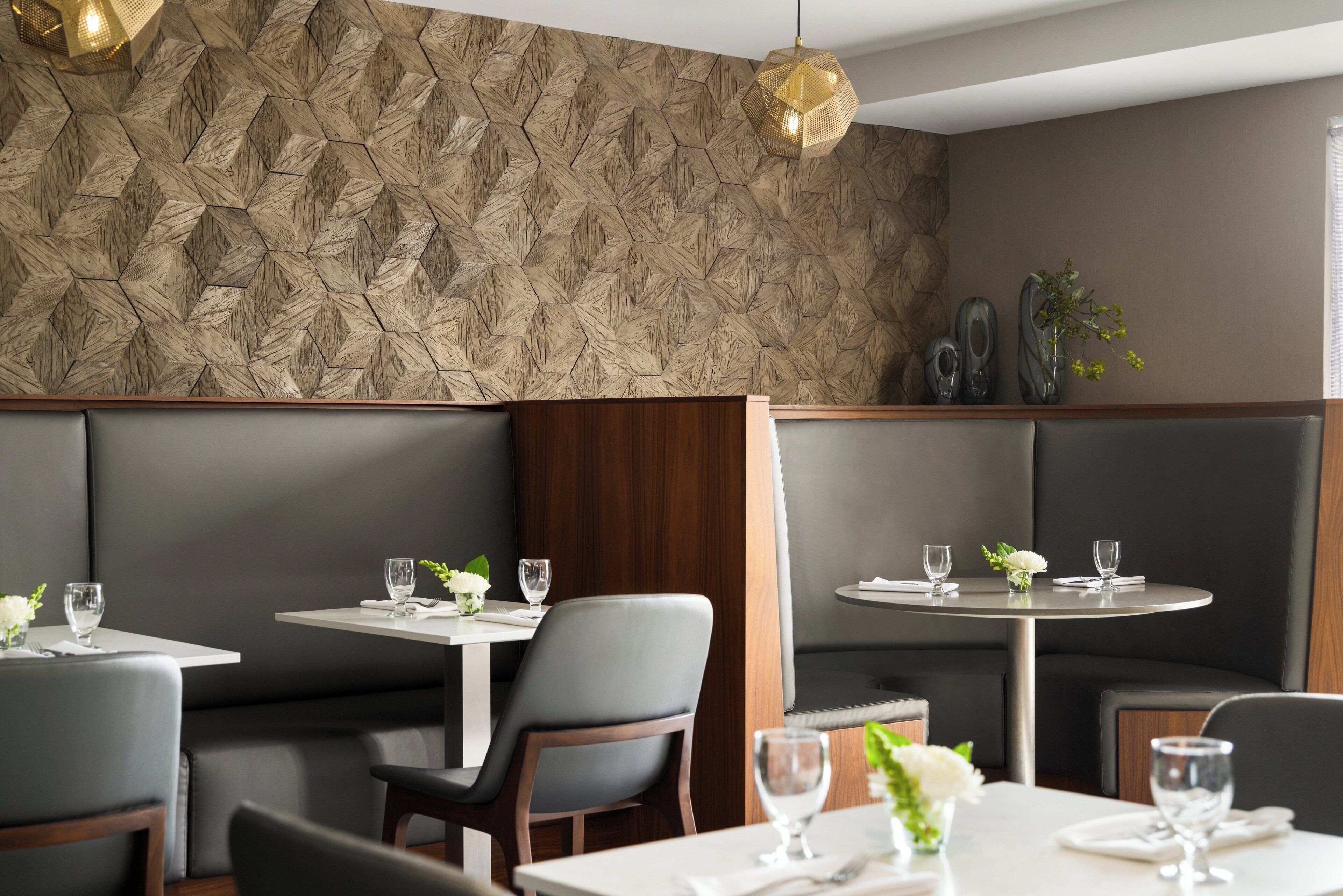 A restaurant with booth seating, round tables, and a textured wall.