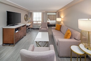 A hotel room with a flat-screen TV, a desk with a chair, a sofa with cushions, a coffee table, and a lamp. - Crowne Plaza Toronto Airport by IHG (Toronto)