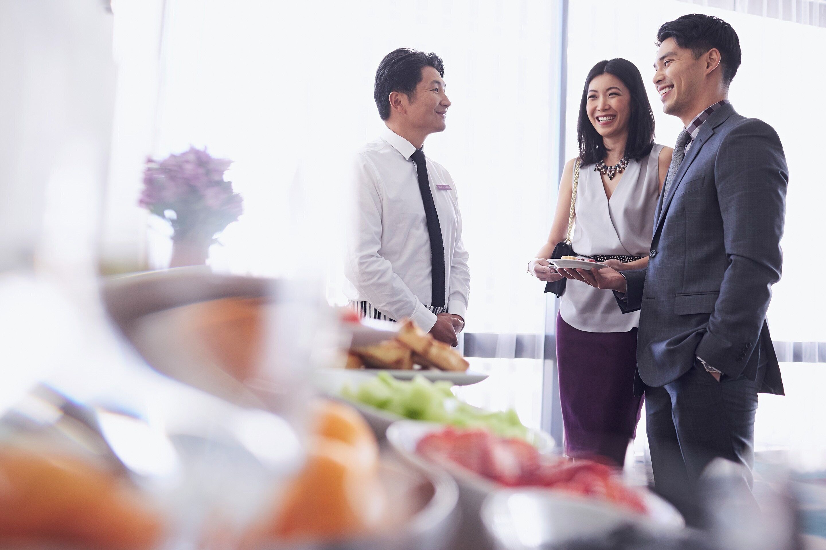 A group of people standing in a room with a buffet table in the foreground.