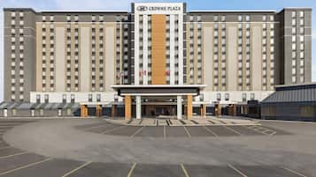 Een groot hotelgebouw met meerdere verdiepingen, een centrale ingang en een parkeerplaats ervoor.