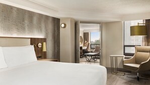 Une chambre d’hôtel avec un grand lit, un bureau, une chaise et une vue sur la ville.