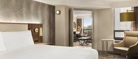 A hotel room with a large bed, a desk, a chair, and a view of the city.