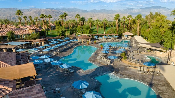 Een resort met meerdere zwembaden, ligbedden en parasols.