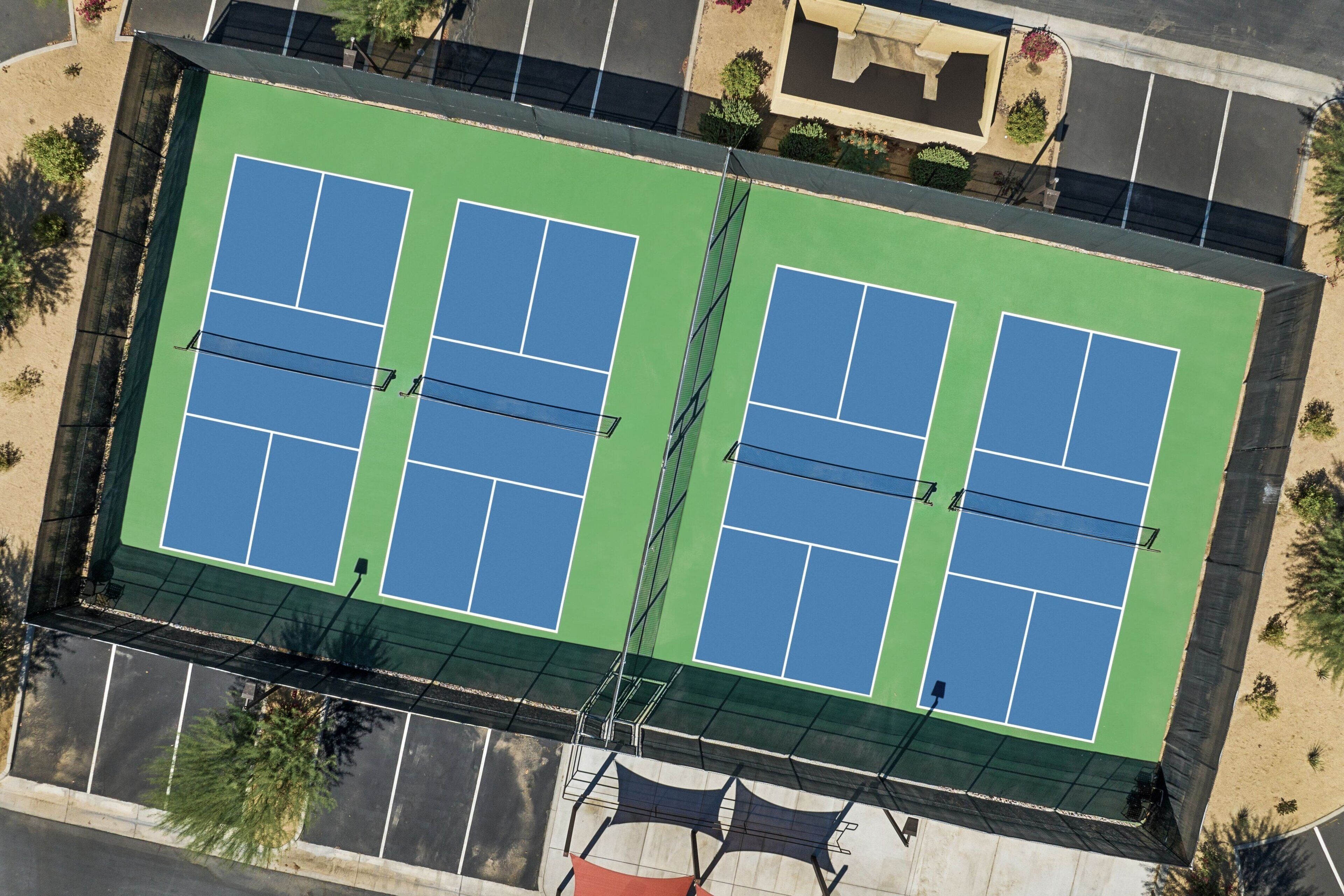 Luchtbeeld van een tennisterreincomplex met meerdere banen, omringd door een parkeerplaats en groen.
