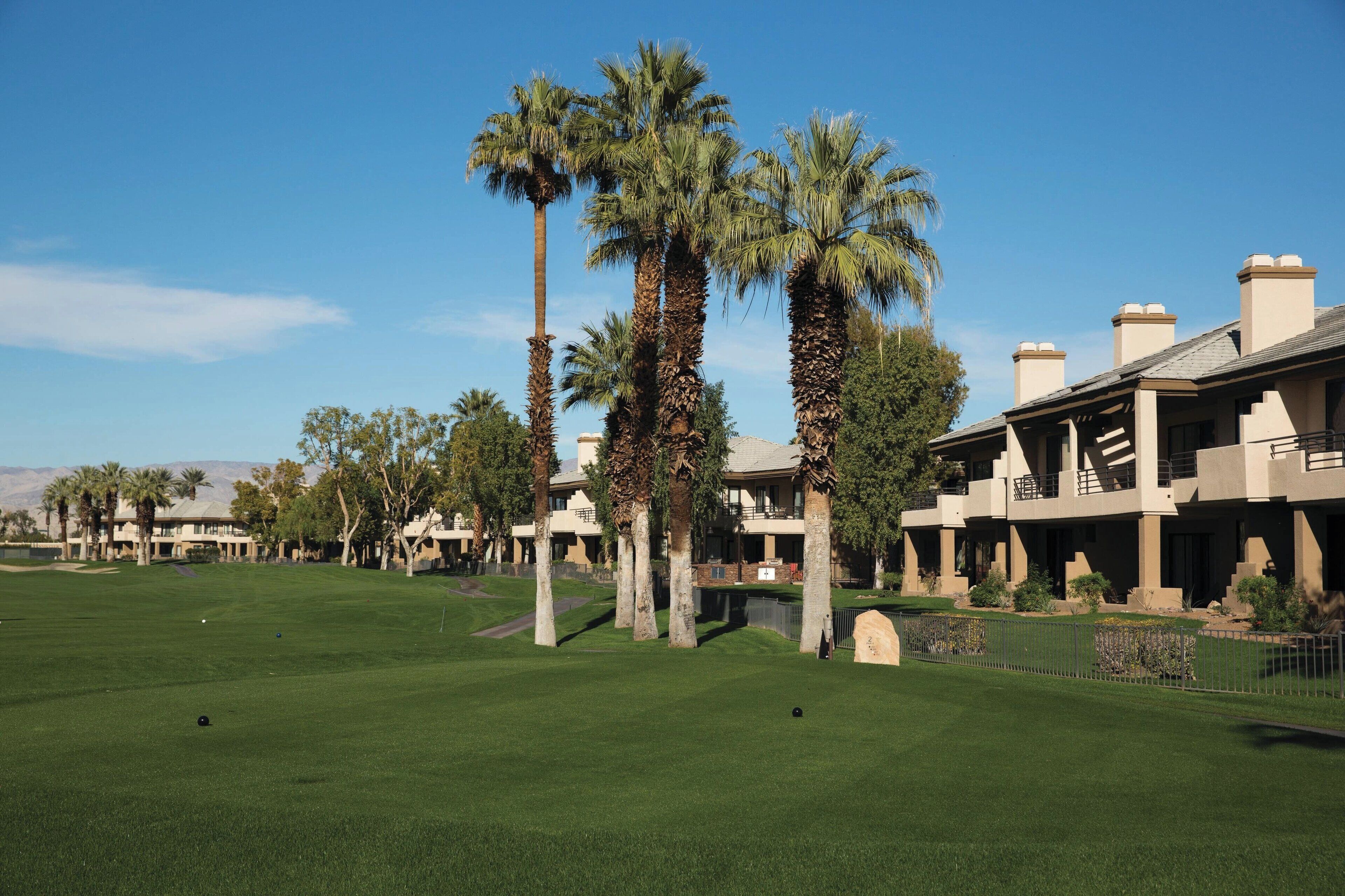A golf course with palm trees and a clubhouse.