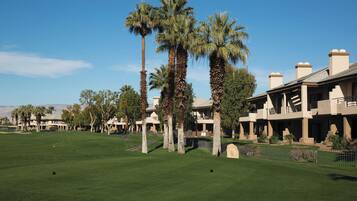A golf course with palm trees and a clubhouse.