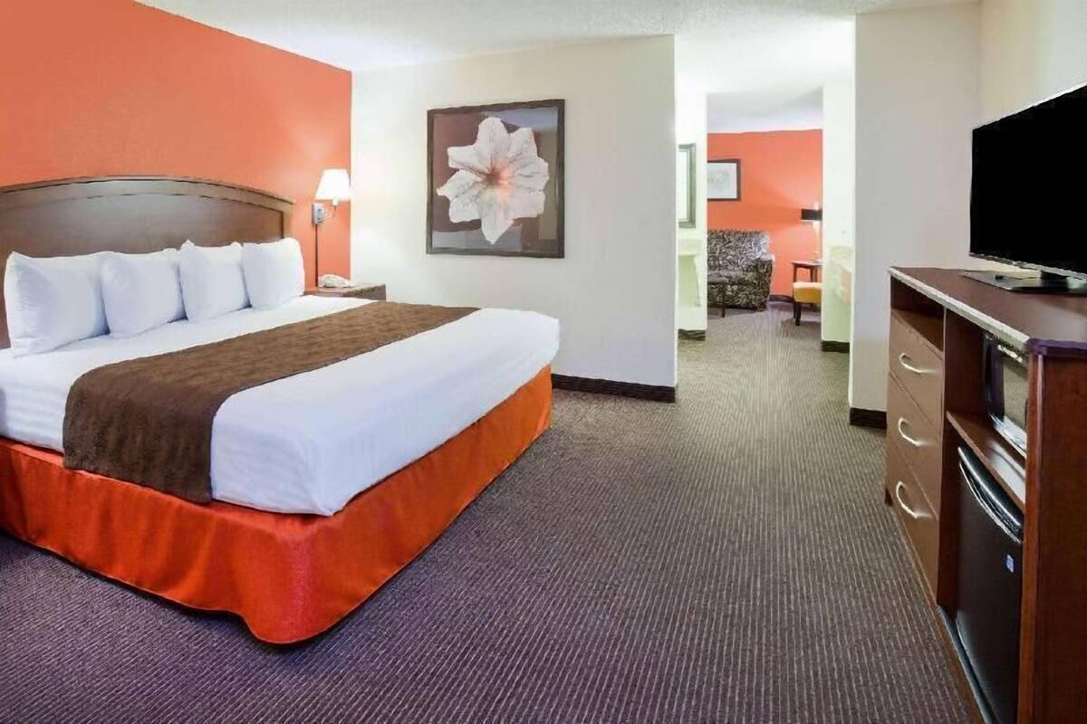Ein Hotelzimmer mit einem Bett, einem Fernseher, einem Schreibtisch und einem Sessel.