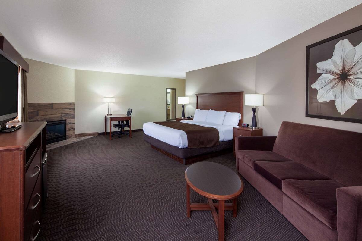 Ein Hotelzimmer mit Bett, einer Couch, einem Schreibtisch und einem Fernseher.