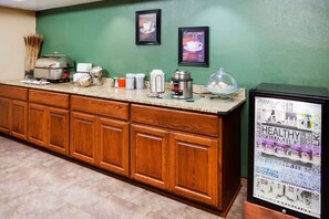 A kitchen with wooden cabinets, a coffee machine, and a refrigerator displaying healthy food items.