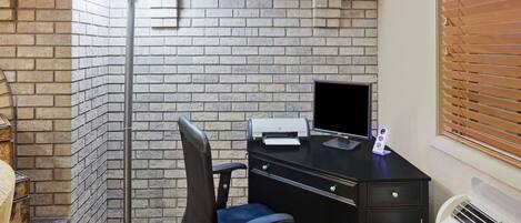 Un petit bureau avec un bureau, une chaise, une imprimante et une lampe.