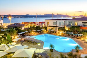 A swimming pool with lounge chairs and umbrellas, surrounded by buildings with a view of the sea and mountains. - Best Western Plus Hotel La Marina (Saint-Raphael)