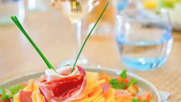 Une assiette de nourriture garnie de ciboulette fraîche, un verre d’eau et une bouteille en arrière-plan.
