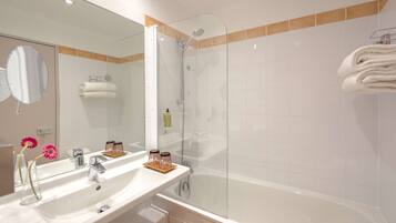 A bathroom with a large mirror, two sinks, a shower, and a bathtub.