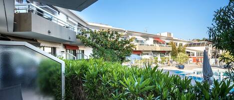 A modern hotel with a pool area, outdoor seating, and a view of the surrounding buildings.