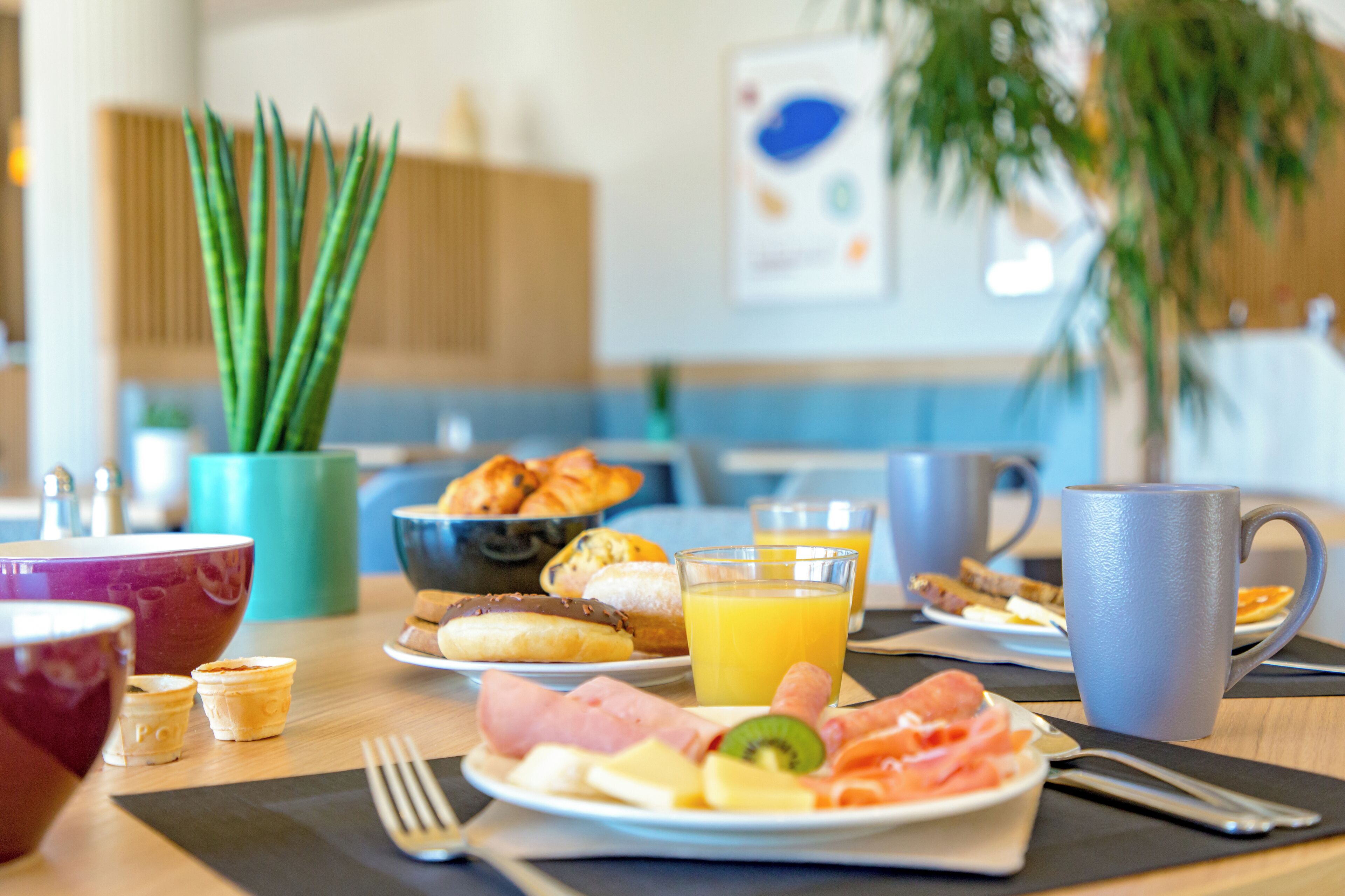 Una mesa de desayuno con diferentes alimentos, una taza de café y un vaso de jugo de naranja.