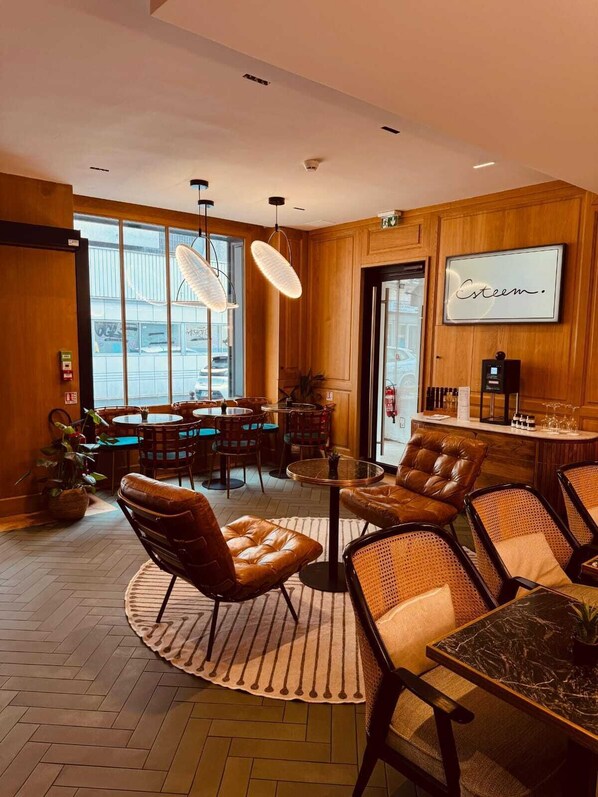 A modern interior with wooden paneling, leather chairs, a round table, and a bar area with a sign reading "Esteem."