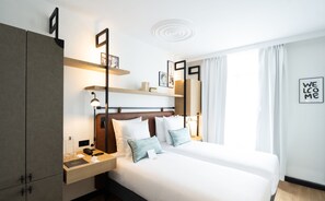 A modern hotel room with a large bed, a wardrobe, a bedside table with a lamp, and a 'Welcome' sign on the wall. - Hotel Esteem Tour Eiffel (Paris)