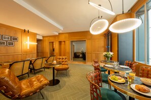A dining area with leather chairs, wooden tables, and pendant lighting. - Hotel Esteem Tour Eiffel (Paris)