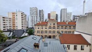 A cityscape with a mix of modern and historic buildings, including a prominent building with a red-tiled roof and a facade with decorative elements. - Hotel Esteem Tour Eiffel (Paris)