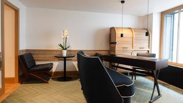 A modern hotel room with a seating area, a small table, and a large window.