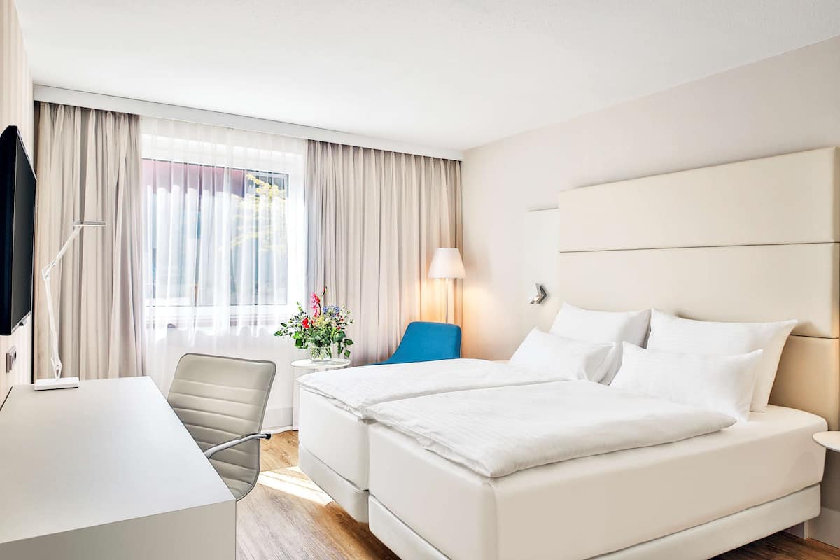 Une chambre d’hôtel avec un grand lit, un bureau, une chaise et une lampe.