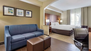A hotel room with a blue sofa, a bed, a desk with a chair, and framed pictures on the wall. - Comfort Inn & Suites Seguin (Seguin)