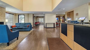 A hotel lobby with a reception desk, a blue sofa, a dining area, and a large window. - Comfort Inn & Suites Seguin (Seguin)