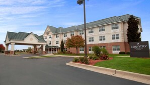 A Country Inn & Suites hotel with a two-story building, a covered entrance, and a well-maintained lawn.