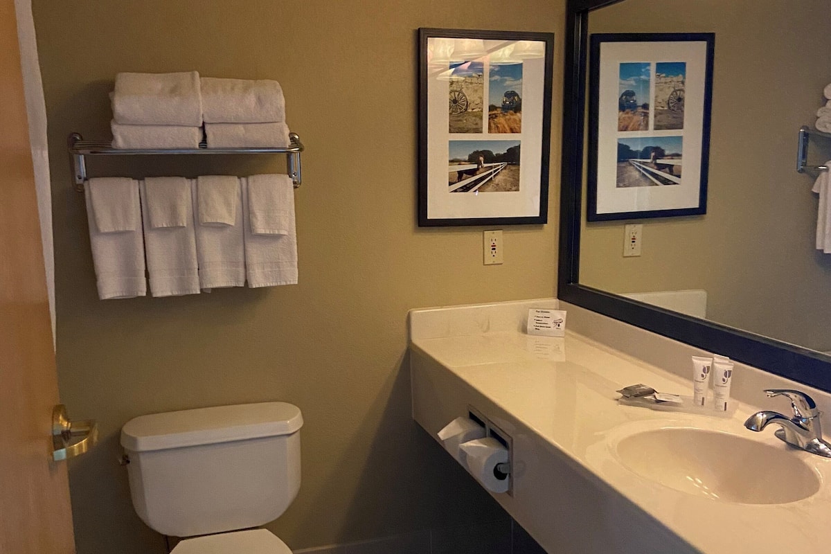 A bathroom with a toilet, sink, and towel rack. There are framed pictures on the wall.