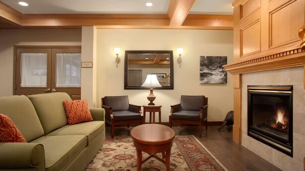 A living room with a green sofa, two armchairs, a small table, a fireplace, and a large mirror.