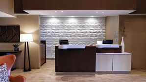 A reception area with a modern design, featuring a reception desk, a seating area with a sofa, and a decorative wall with a wavy pattern. - Fairfield Inn & Suites by Marriott Rockingham (Rockingham)